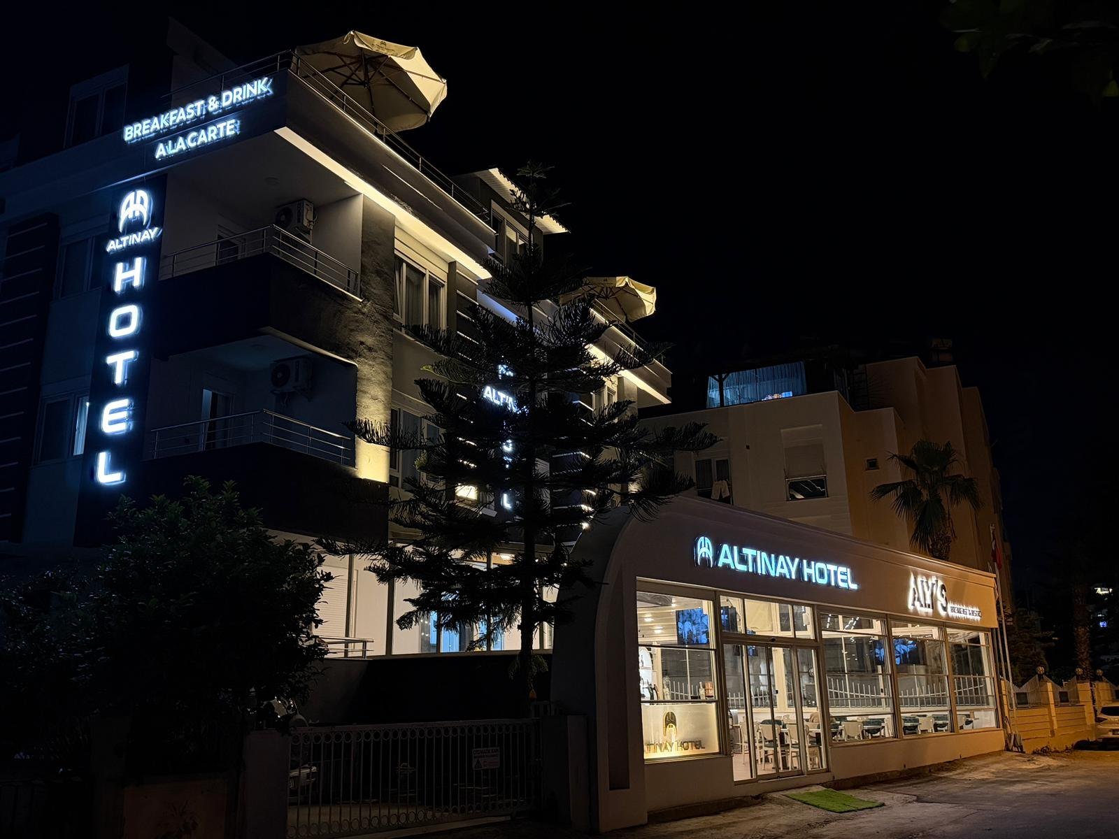 Altınay Hotel Antalya gece dış görünüm, ışıklı ALTINAY HOTEL tabelası ve ALY'S Bistro